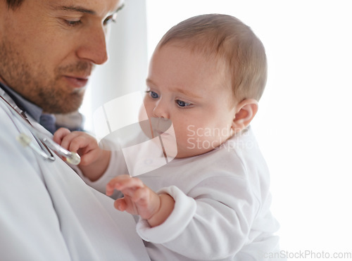 Image of Doctor, pediatrician and baby playing with stethoscope for healthcare assessment, medical support and growth. Newborn kids, man and pediatrics service in clinic, hospital and playful children