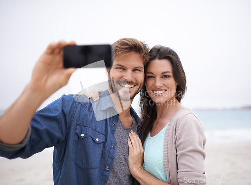 Image of Selfie, love and couple hug at beach for travel, photo and freedom outdoors together. Smile, embrace and traveling influencer people live streaming for blog, followers or social media profile picture