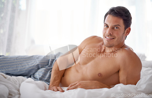 Image of Sexy, smile and portrait of a man on a bed for relaxing, comfort and rest in pyjamas. Comfy, cozy and handsome young man content in the bedroom, smiling and confident to relax on the weekend