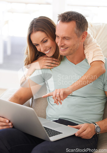 Image of Happy couple, computer and pointing on home internet for online planning, website and to check application together. Hug, love and mature partner, woman or people on sofa reading on laptop technology