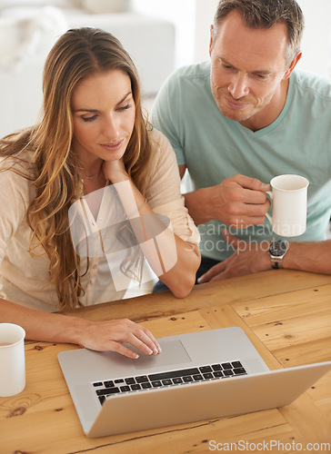 Image of Laptop, home and couple reading online, scroll on internet together and check website or application for information. Mature partner, woman or people on computer or pc with coffee or tea at table