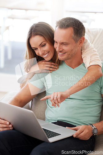 Image of Laptop, pointing and mature couple on home internet for online planning, website and to check application together. Hug, love and happy woman, partner or people on sofa, choice or reading on computer