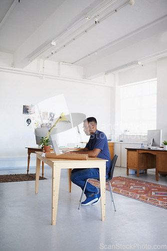 Image of Creative, office or black man typing on laptop working on a blog project, digital or online research. Coworking, planning or focused African designer working on website in startup company agency