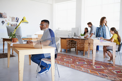 Image of Coworking, office or black man typing on laptop working on a creative project, digital or online research. Computer, planning or focused African designer working on website in startup company agency