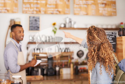 Image of Woman, coffee shop and pointing at menu on wall with barista, notes and service for good customer experience. Male waiter writing, lady and talking with choice, decision and order from bakery shop