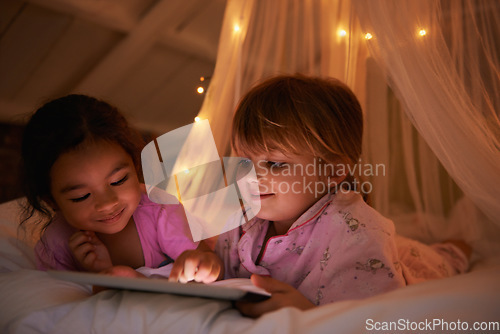 Image of Night, bed and girls with a tablet, games and playing for fun, happiness and relax together. Female kids, children and young people with technology, entertainment and cheerful with a smile or evening