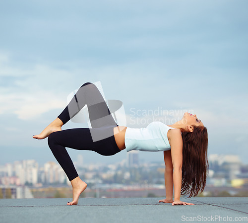 Image of Fitness, yoga and balance, woman on rooftop in city, stretching back for wellness with reverse plank. Health care, pilates and mindfulness, body workout for girl and cityscape view and sky from roof.