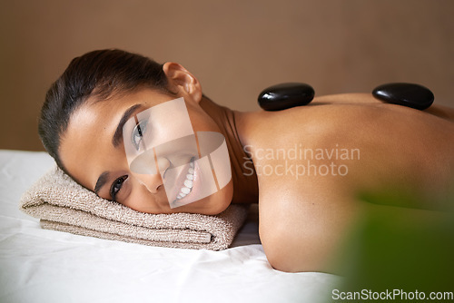 Image of Portrait of happy girl, rock or back massage in spa to relax for zen, resting or wellness physical therapy. Face of woman smiling in salon to exfoliate for body healing treatment or hot stone therapy