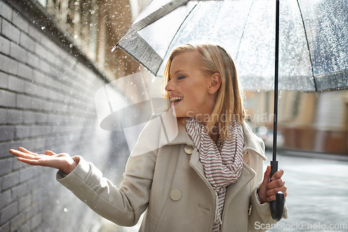 Image of Smile, happy woman and rain feel in the city with umbrella, freedom and happiness on holiday. Winter weather, raining and urban street with a young female person on a sidewalk and vacation outdoor