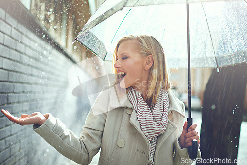 Image of Smile, happy woman and rain feeling water in the city with umbrella, freedom and happiness. Winter weather, raining and urban street with a young female person on a sidewalk and vacation outdoor