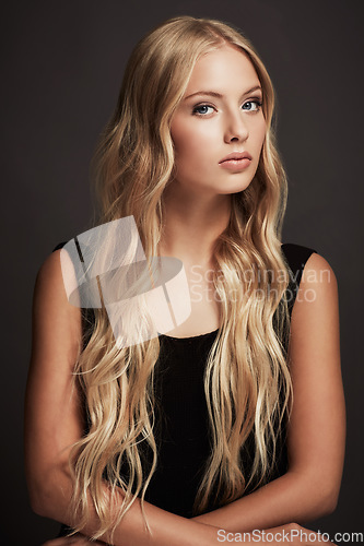 Image of Face, beauty and portrait of a woman with makeup, cosmetics and long hair in studio. Serious female aesthetic model with a skin glow, luxury skincare and fashion on a grey or dark background