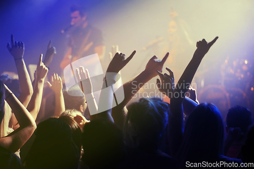Image of Hands in air, people dancing at concert or music festival with neon lights and energy at live event. Dance, fun and excited crowd of fans in arena for rock band, musician performance and spotlight.