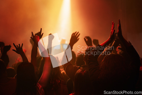 Image of Hands of people in crowd dancing at concert or music festival, neon lights and energy at live event. Dance, applause and group of excited fans in silhouette at rock band performance with lighting.