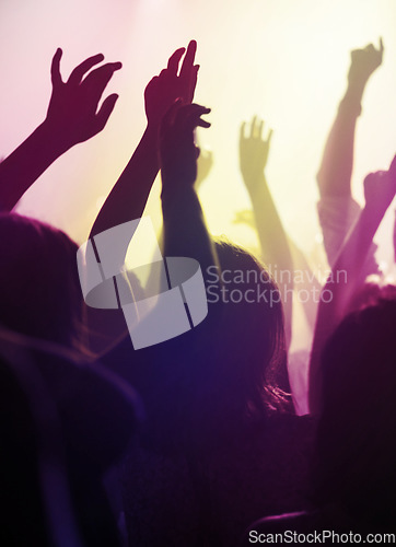 Image of Hands, dancing and fans at concert or music festival from back, neon light and energy at live event. Dance, fun and group of excited people in arena at rock band performance or audience at rave party