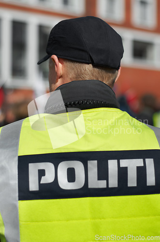 Image of Law enforcement, protection and security with back of police officer in city for peace, safety or rally. Emergency services, justice and guard with person in Denmark street for help, order and arrest