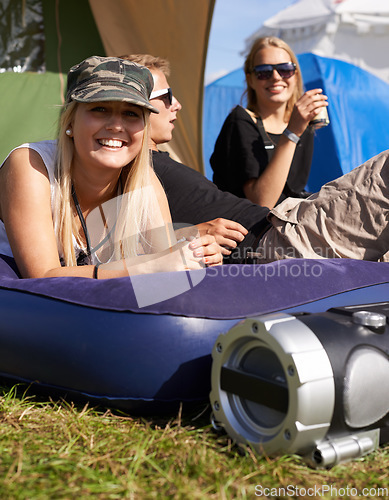 Image of Women, relax and mattress at outdoor festival with happiness, camping or sunshine on grass. Friends, portrait and freedom with smile, support and summer vacation on camp, event or adventure in nature