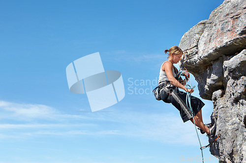 Image of Rock climbing, blue sky and freedom with woman on mountain cliff for adventure or travel with space. Strong, challenge and mockup with female climber training in nature for courage, safety or workout