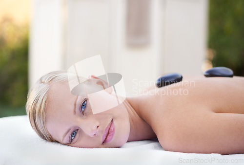 Image of Woman in portrait, hot stone massage in spa with wellness, healing and holistic treatment at luxury resort. Stress relief, zen and female person with rocks on back for self care and physical therapy