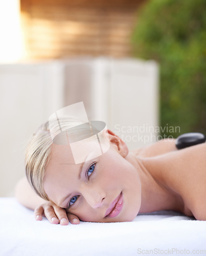 Image of Face of woman, hot stone massage at spa with healing and wellness, holistic treatment at luxury resort. Stress relief, zen and female person with rocks on back in portrait, self care and therapy