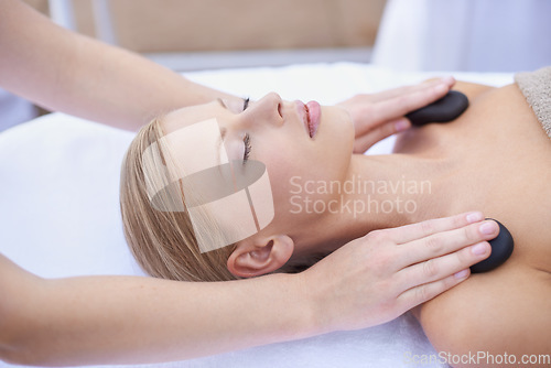 Image of Woman getting hot stone massage, hands of masseuse in spa and healing holistic treatment with zen at wellness resort. Rocks on shoulders, peace with therapy, alternative medicine and self care