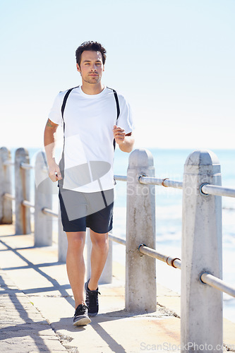 Image of Man, fitness and running by the beach for exercise, workout or training in the nature outdoors. Fit, active or athletic male runner exercising on the ocean coast for run, healthy cardio and wellness
