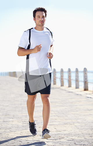 Image of Man, fitness and running by the beach for workout, exercise or training in the nature outdoors. Fit, active or athletic male runner exercising on the ocean coast for run, healthy cardio and wellness