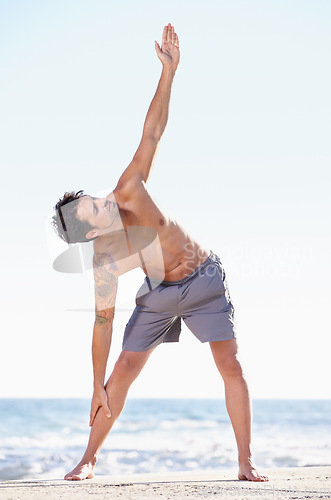 Image of Fitness, man and stretching body on beach for yoga or getting ready for exercise, workout or training in nature. Fit, active or muscular male yogi in warm up stretch, cardio or exercising by an ocean