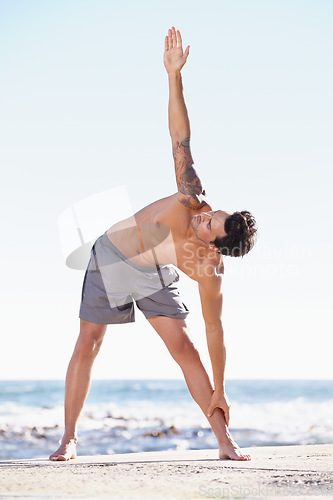 Image of Fitness, man and stretching body on beach for exercise, yoga or getting ready for workout or training in nature. Fit, active or muscular male yogi in warm up stretch, cardio or exercising by an ocean