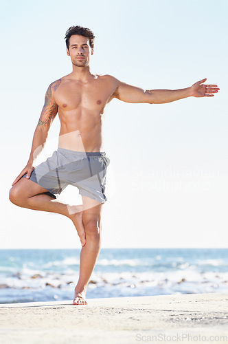 Image of Fitness, man and yoga tree pose on beach for exercise or stretching body in workout or training in nature. Fit, active or male yogi in warm up stretch, cardio or exercising in balance on ocean space