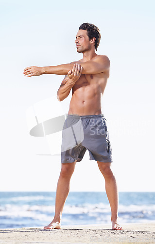 Image of Fitness, man and stretching arms on beach getting ready for body exercise, workout or training in nature. Fit, active or muscular male person in warm up arm stretch for cardio or exercising by ocean
