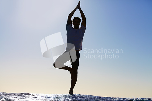 Image of Man, silhouette and yoga in meditation on beach for spiritual wellness, inner peace or mental wellbeing in nature. Calm male yogi in tree pose for balance, healthy body or mindfulness by the ocean