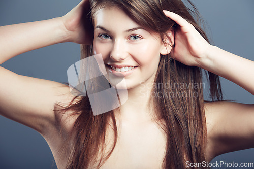 Image of Beauty, face and smile portrait of a woman in studio with hands in hair care, makeup and cosmetics. Headshot of happy young female model on a grey background for natural glow, skincare or dermatology