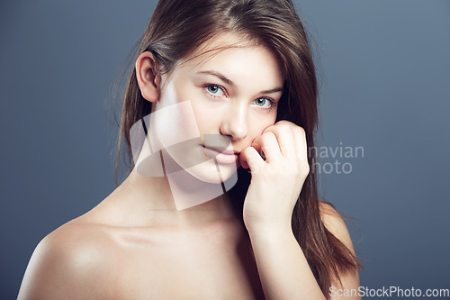 Image of Natural, face and portrait of a shy woman in studio with a glow, beauty and cosmetics. Headshot of a young female model on a grey background for shine, hair care and facial skincare or dermatology