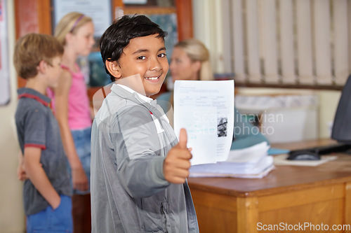 Image of Portrait, child and student with thumbs up and paper for test or assignment in classroom. Happiness, hand gesture and kid with like emoji, agreement and learning in elementary school for education.