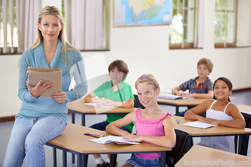 Image of Portrait, teacher and woman with students in classroom, smile and holding folder. Happiness, female educator and group of children ready for learning, education or teaching in elementary school class