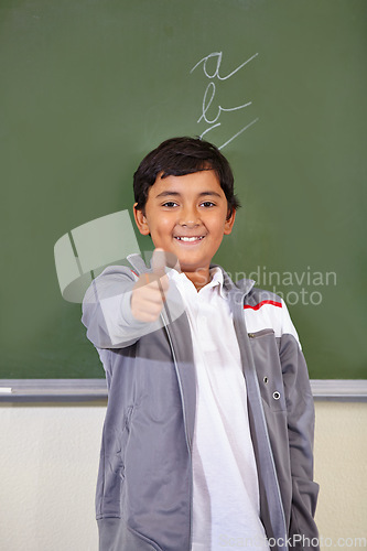 Image of Portrait, child and thumbs up of student on chalkboard in classroom, elementary school and mockup. Blackboard, education and kid with hand gesture for like emoji, agreement and learning with a smile.