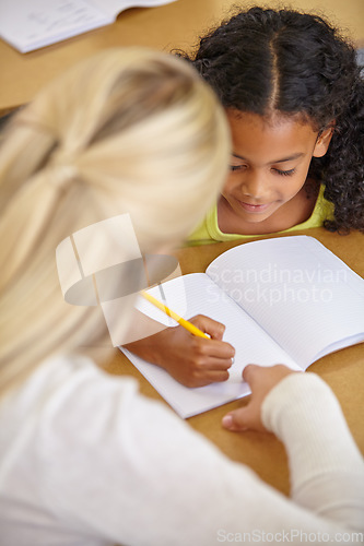 Image of Teacher helping student in classroom, education and writing in notebook with pencil, teaching and learning for development. Scholarship, academic study and young girl and woman in lesson at school