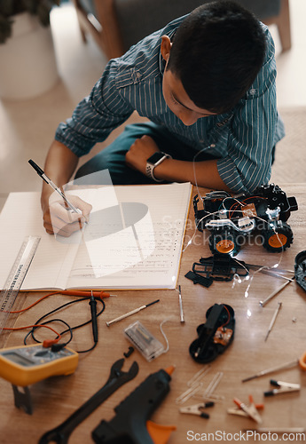 Image of Education, writing in notebook and kid with robotics homework, homeschool and science for tech project. Taking notes, car robot and boy child with knowledge, learning and studying in house top view