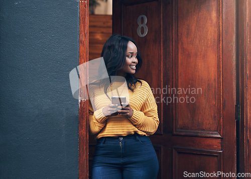 Image of Doorway, woman and phone for social media, texting and happy while reading message in front of house. Smartphone, influencer and african female online for blog, networking or property app review