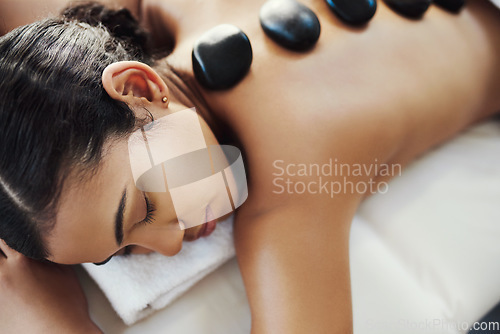 Image of Woman, relax and sleeping in rock massage at spa for skincare, beauty or body treatment at salon. Calm female asleep with eyes closed and hot rocks on back for healthy physical therapy at the resort