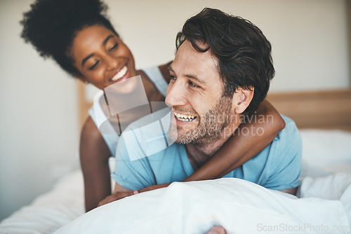 Image of Happy couple, bed and hug laughing for morning, relax or bonding relationship at home. Interracial man and woman smiling, hugging and laugh in joyful happiness or relaxing weekend together in bedroom