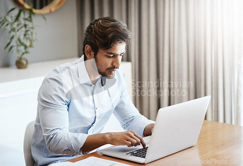 Image of Serious man, remote work and typing on laptop in home at table for digital planning, research and online network. Focused male freelancer working on computer keyboard, internet technology and website