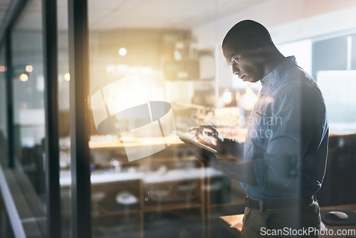 Image of Black man in business, tablet and night at office, information technology and software update. Male programmer work late, overtime and deadline with focus, concentration and cyber security upgrade