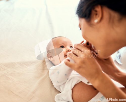 Image of Smile, love and a mother with her baby on the bed in their home together for playful bonding. Family, kids and a happy young mama spending time with her newborn infant in the bedroom for fun or joy