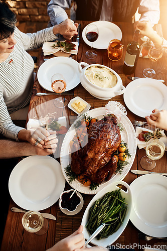 Image of Food, celebration and people praying and holding hands at a table together for thanksgiving holiday. Above group of family or friends pray for gratitude for healthy lunch, turkey and wine in house