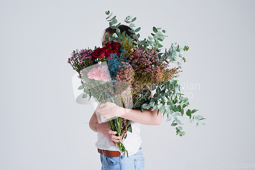 Image of Nature, gift and woman with flowers, creative aesthetics and beauty against a grey background. Female person, model and girl with a floral present, bouquet and covering face with natural products