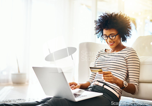 Image of Young woman, laptop and credit card while doing online shopping sitting on ground. Home, happiness and computer internet deal of African female person on an ecommerce app reading banking details