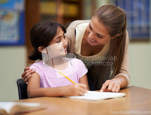 Image of Study, education or learning with a student and teacher in a classroom together for writing or child development. School, scholarship and teaching with a woman educator helping a girl child in class