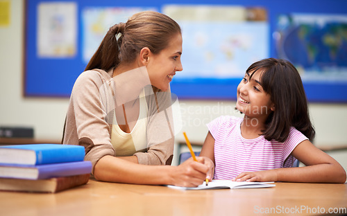 Image of School, education or learning with a girl student and teacher in a classroom together for writing or child development. Study, scholarship and teaching with a woman educator helping a child in class