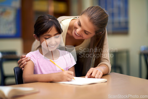 Image of School, education or study with a student and teacher in a classroom together for writing or child development. Learning, scholarship and teaching with a woman educator helping a girl child in class